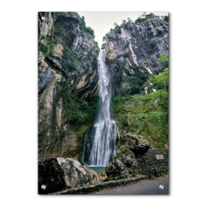 מפל מים שוצף יורד מצוק תלול, מוקף בצמחייה ירוקה מרהיבה, אל בריכה שקטה בבסיסו.