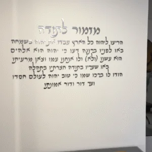 מזמור לתודה באותיות כסף מרחפות על קיר שיש לבן עם מסגרת זהב, בחלל אוכל יוקרתי.